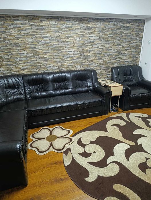 Vand coltar extensibil impreuna cu un fotoliu din piele neagra.