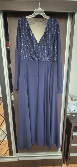 Rochie lungă de seară albastru închis, cu aplicații de paiete strălucitoare pe bust și mâneci lungi din voal.