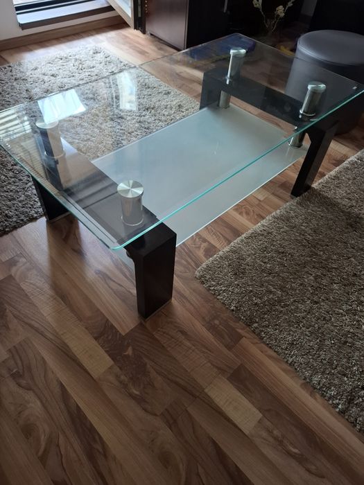 Măsuță de cafea modernă, realizată dintr-o combinație de sticlă, metal și lemn .