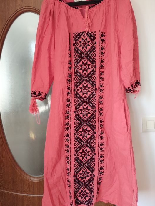 Rochie tradițională ie,roz corai,cu motive geometrice brodate,are buzunare lateral