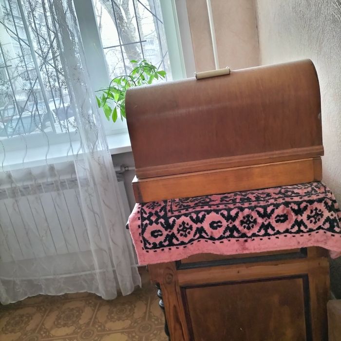 Машинка швейная электрическая с ножным приводом в рабочем  состоянии.