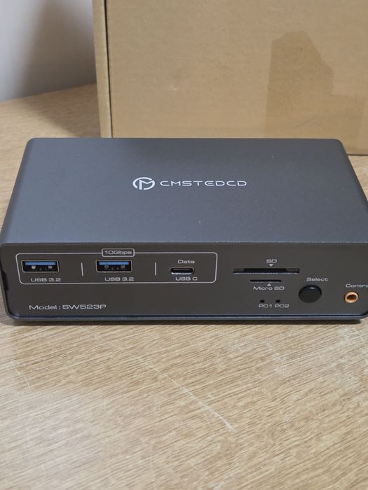 KVM докинг станция (модел CMSTEDCD SW523P), която позволява споделянето на монитори и периферия между два компютъра.
