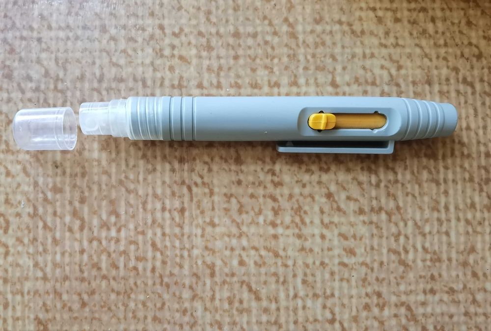 Уред с четка и пръскаща част за почистване на лещи и обективи