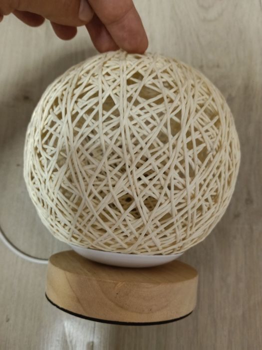 lampă de masă are un abajur sferic din ratan țesut manual și o bază din lemn.