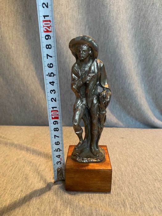 стара калаена статуя на човек с шапка върху дървена основа