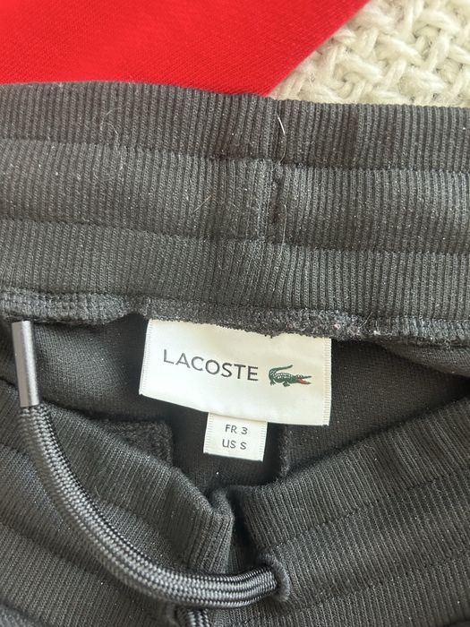 Trening Lacoste format din 2 piese pantaloni negri cu bluza roșie. mărimea M la bluză și mărimea S la pantaloni