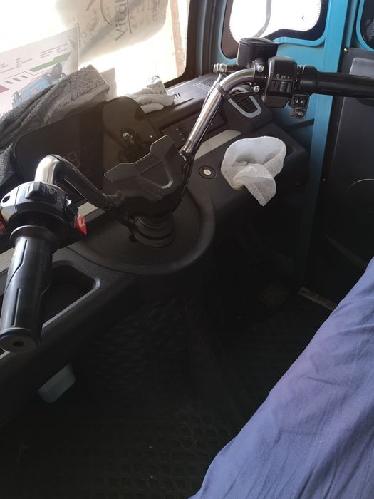 Triciclu electric utilitar cu cabină dublă și benă.