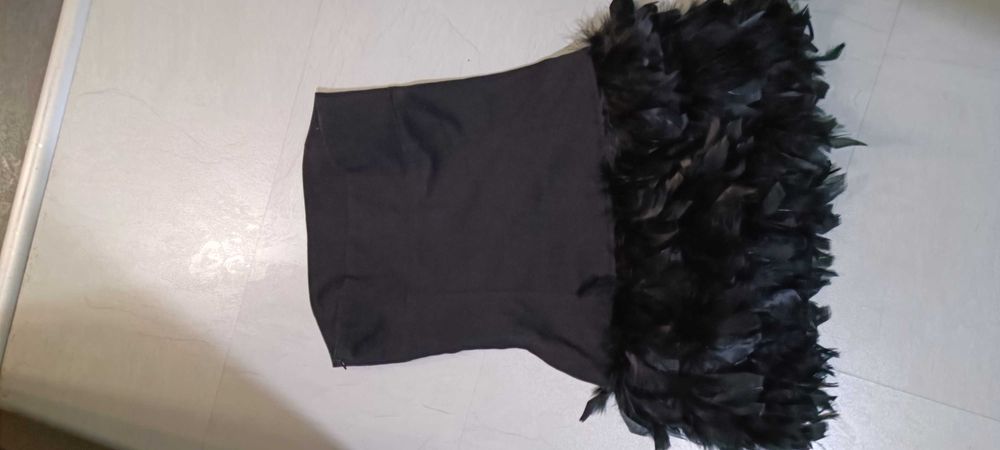 Малка черна рокля с естествени пера в долната част.