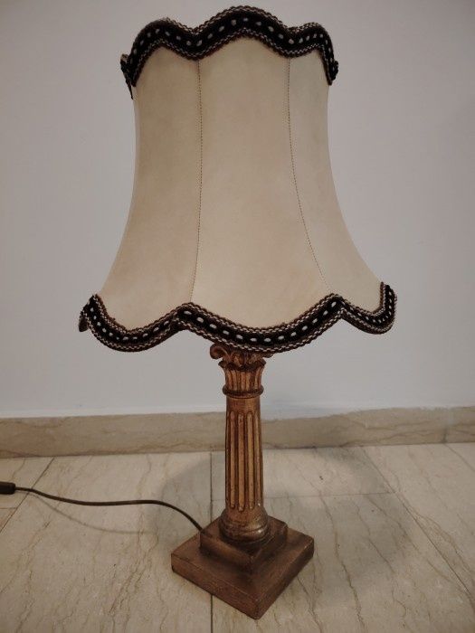 Această candelabrului antic și elegant are o bază din lemn sculptată în stil Empire și Aba, iar abajurul este din material textil în nuanțe calde.