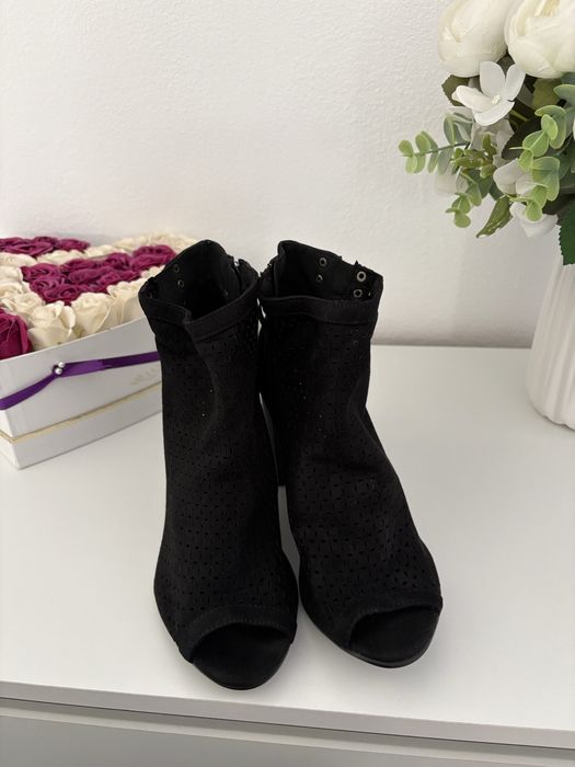 Vand botine negre din piele întoarsă au un design perforat și un vârf deschis.