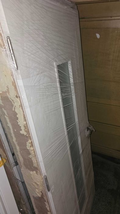 Бяла, плътна интериорна врата с каса и перваз.