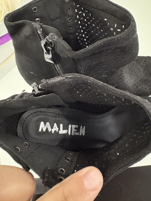 Vand botine negre din piele întoarsă au un design perforat și un vârf deschis.