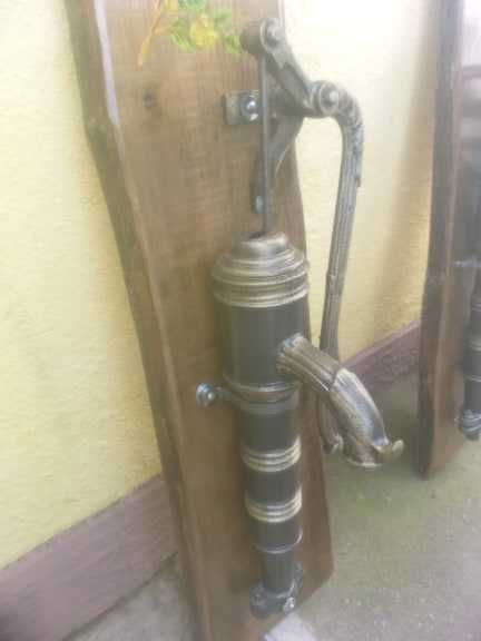 Fantana arteziana din fonta asezata pe un suport de lemn pictata