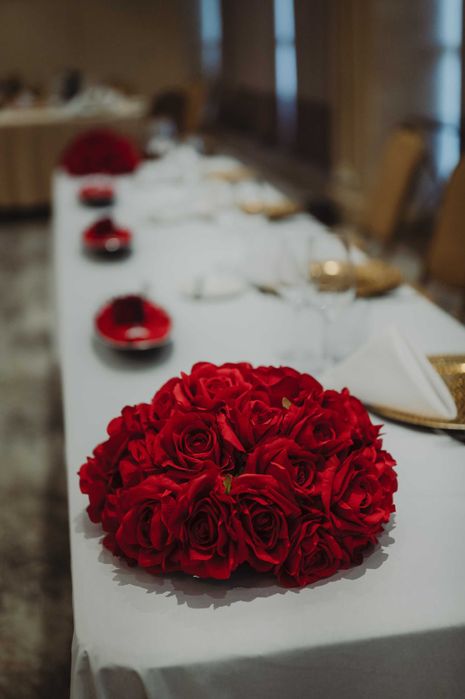 Бяла метална арка с червени рози и друга сватбена украса