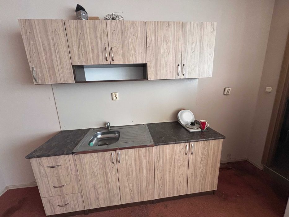 Кухненско обзавеждане с мивка и смесител, маса с три стола и секция