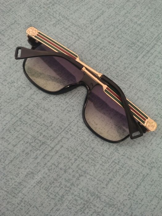 Ochelari de soare unisex cu ramă metalică aurie și detalii colorate.