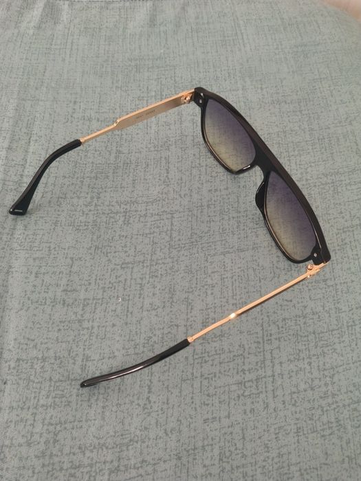 Ochelari de soare unisex cu ramă metalică aurie și detalii colorate.