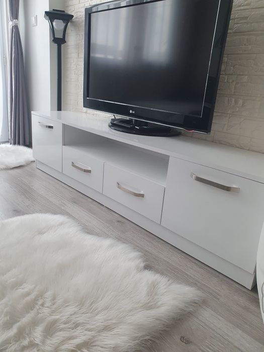 ТВ шкаф с две лавици, бял гланц и плавно затваряне.