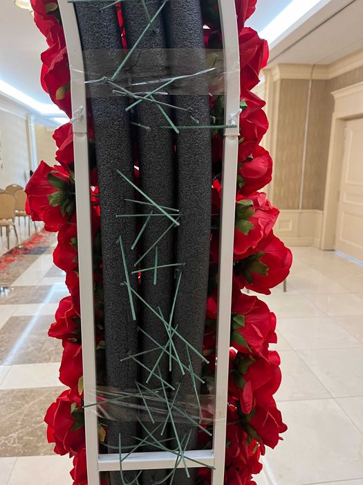 Бяла метална арка с червени рози и друга сватбена украса