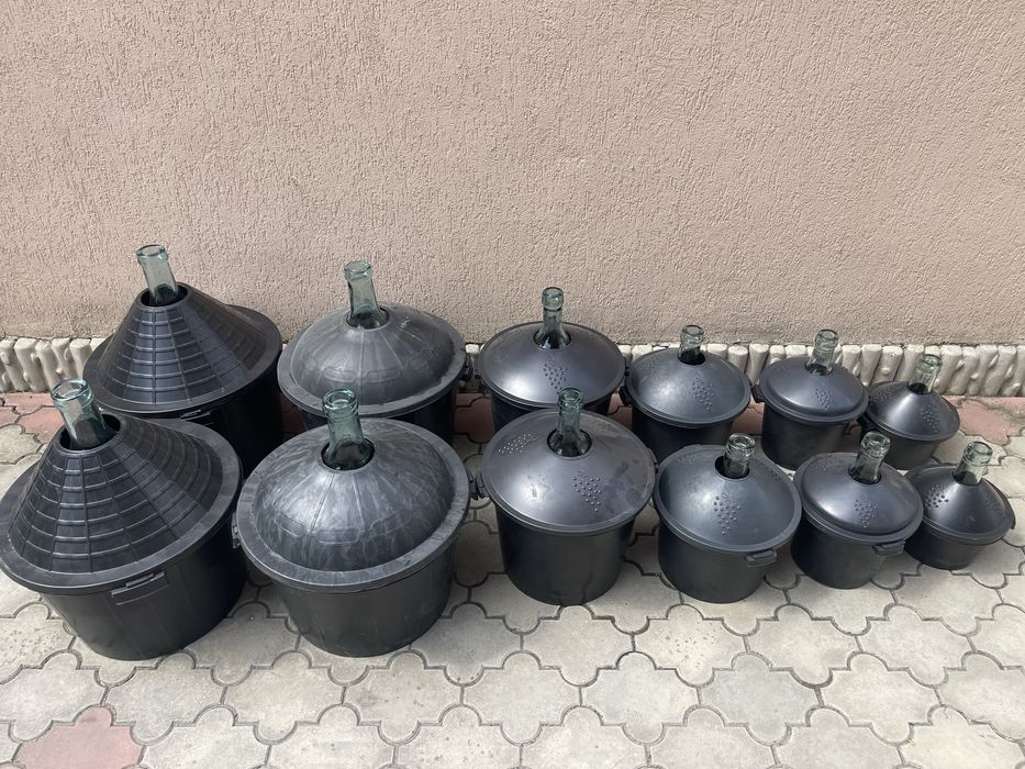 Damigeană din sticlă cu coș din plastic .