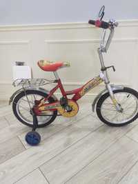 Детский велосипед с двумя задними колесами.