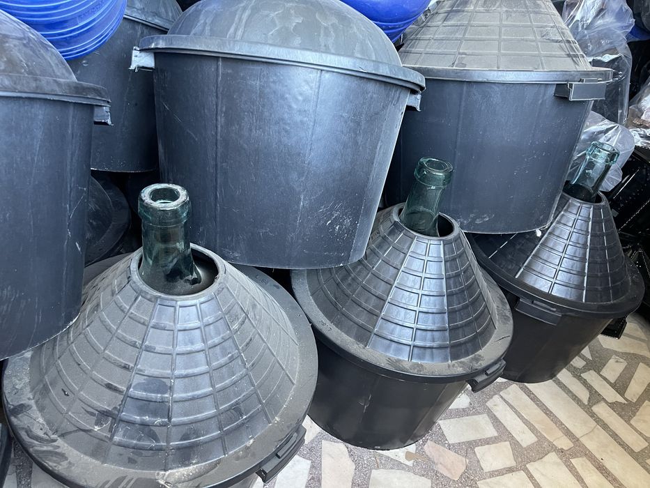 Damigeană din sticlă cu coș din plastic .