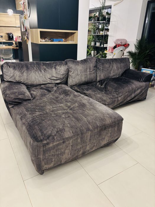 Canapea mare din piele maro, cu husa gri si o nevoie de reparatie