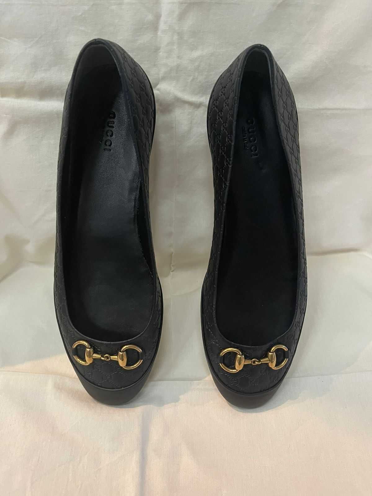 Кожаные балетки Gucci с черной монограммой знака и золотая пряжка.