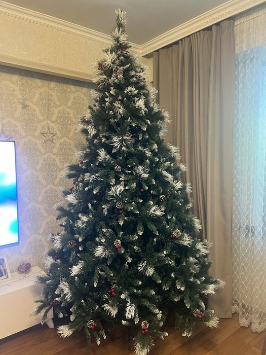 Новогодняя елка украшенная снегом, ягодами и шишками.