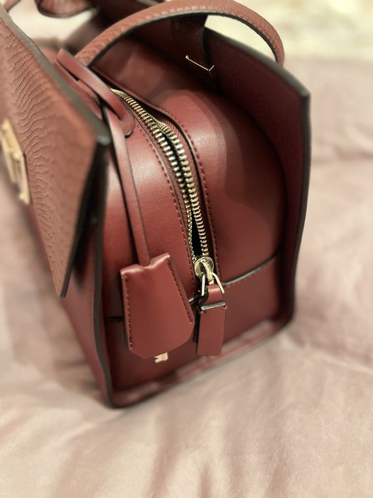 Geantă Guess bordo elegantă cu detalii aurii și textură snake