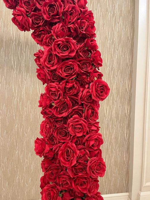 Бяла метална арка с червени рози и друга сватбена украса