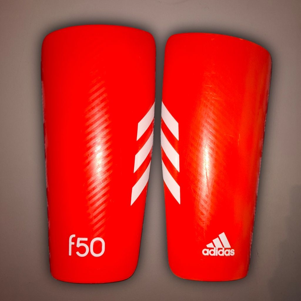 Apărători Adidas f50 portocalii (13,5×9 cm) – super ușoare și stilate