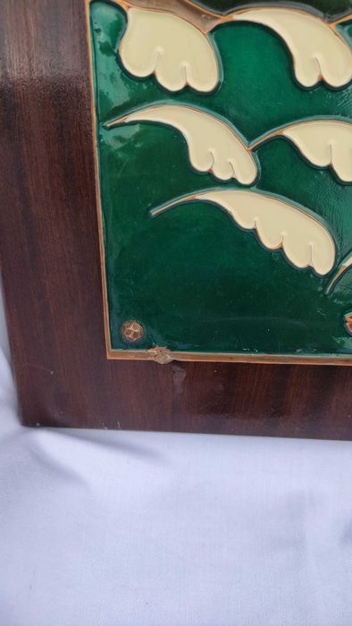 Голяма цветна медна пластика върху дървена основа