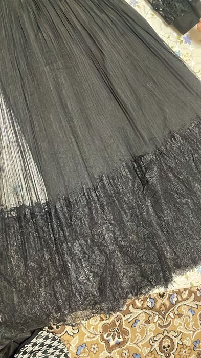 Черное платье с плиссированной юбкой из тюля и кружевными рукавами.