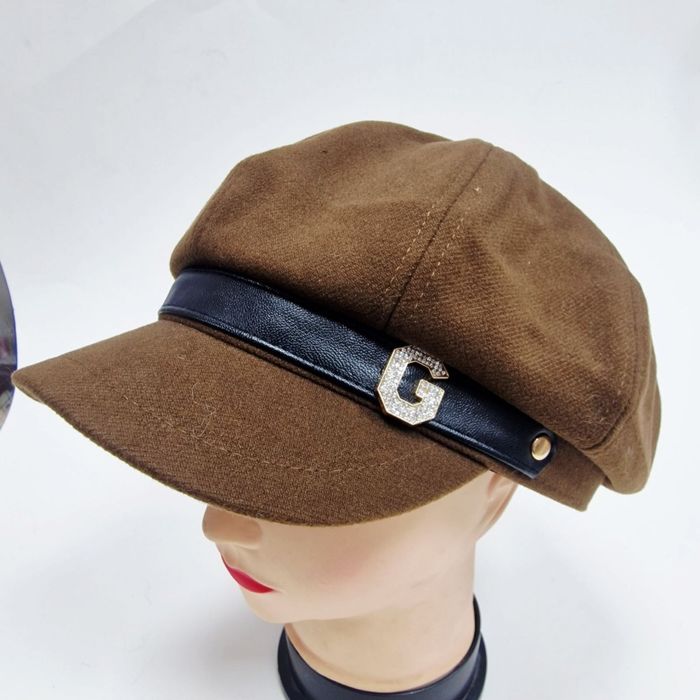 Елегантна дамска шапка тип фуражка с декоративна лента и метално лого.