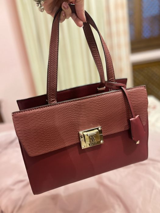 Geantă Guess bordo elegantă cu detalii aurii și textură snake