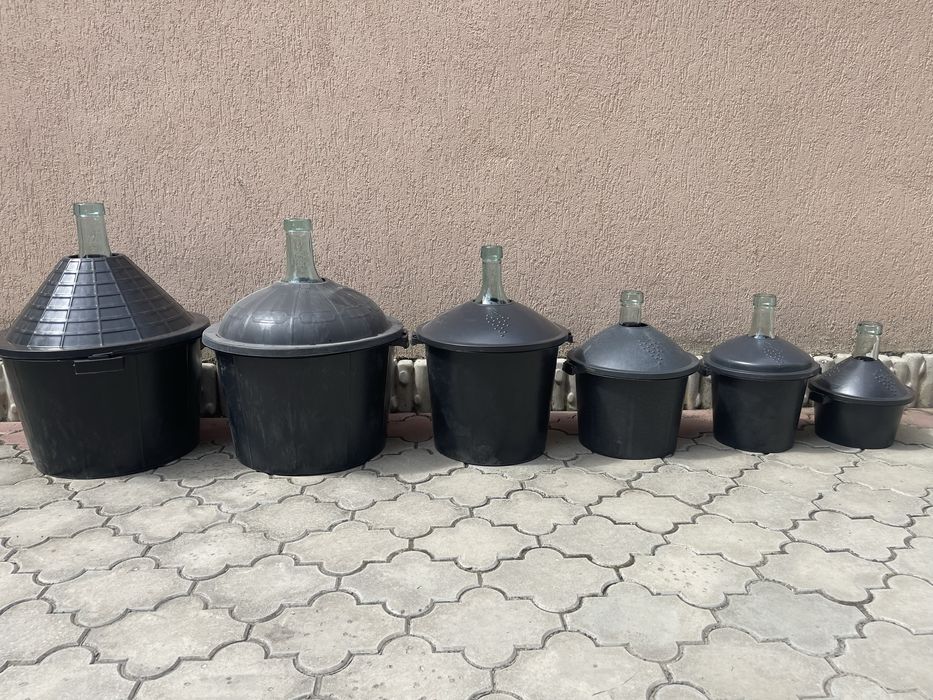 Damigeană din sticlă cu coș din plastic .