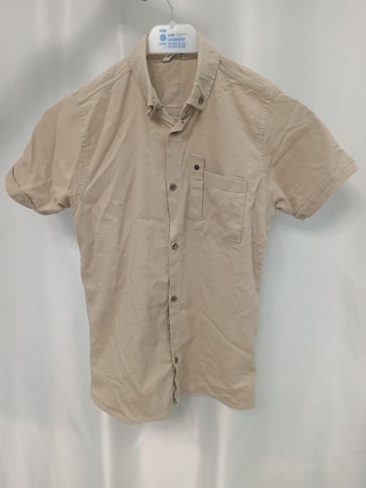 Бежевая рубашка с коротким рукавом.