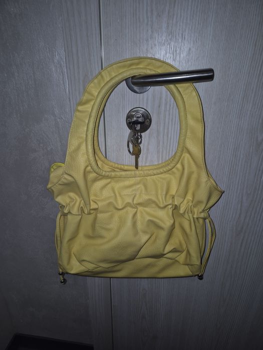 Жълта чанта с цип, вътрешен джоб и връзки за ефектно пристягане .